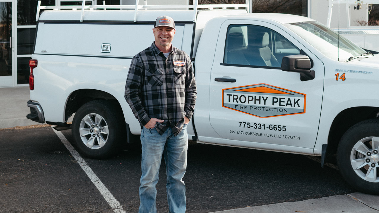 Mike Lee, founder of Trophy Peak Fire Protection, standing in front of company truck during 20 year anniversary.